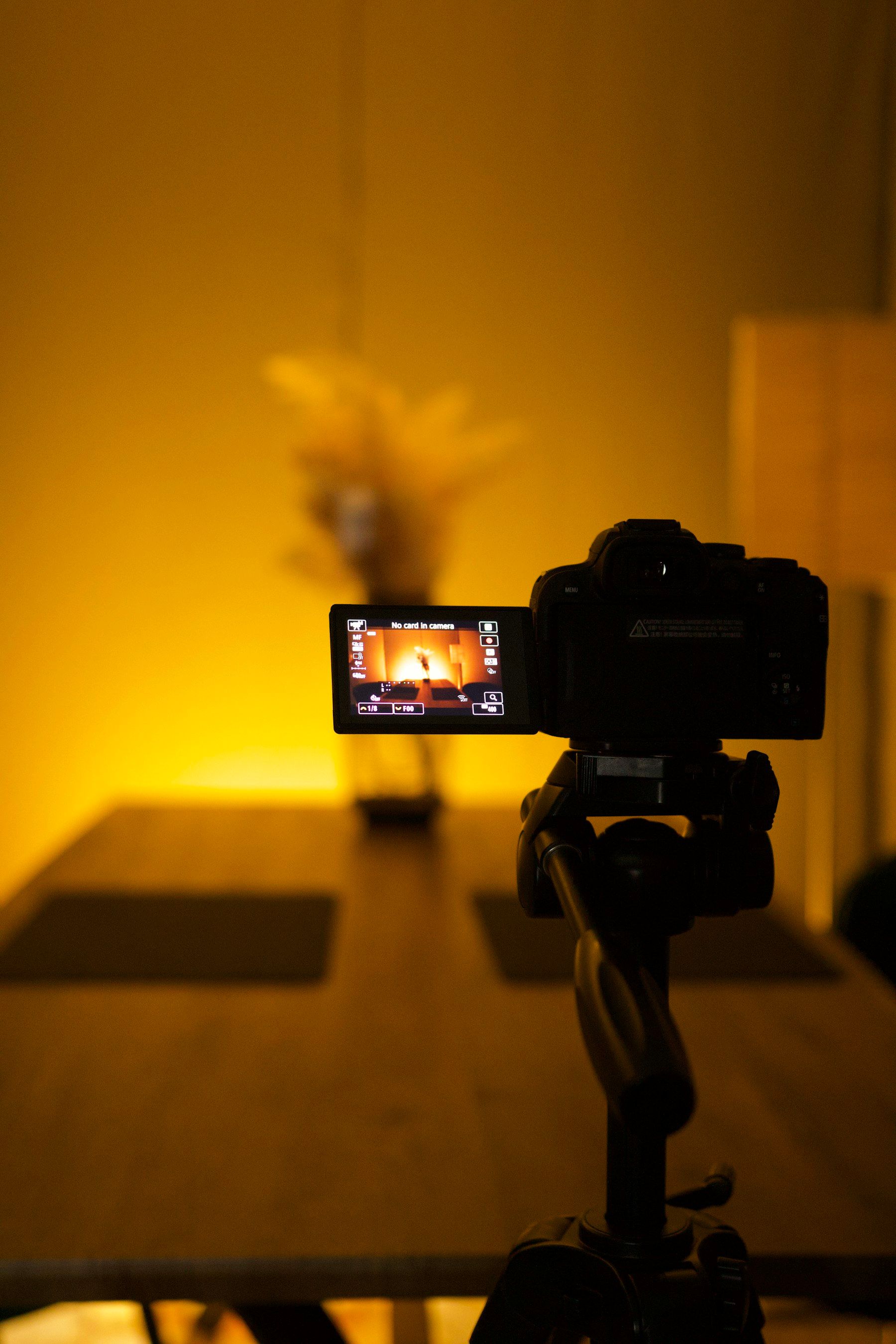 Un appareil photo sur trépied filme une table, dans une lumière jaune et chaleureuse
